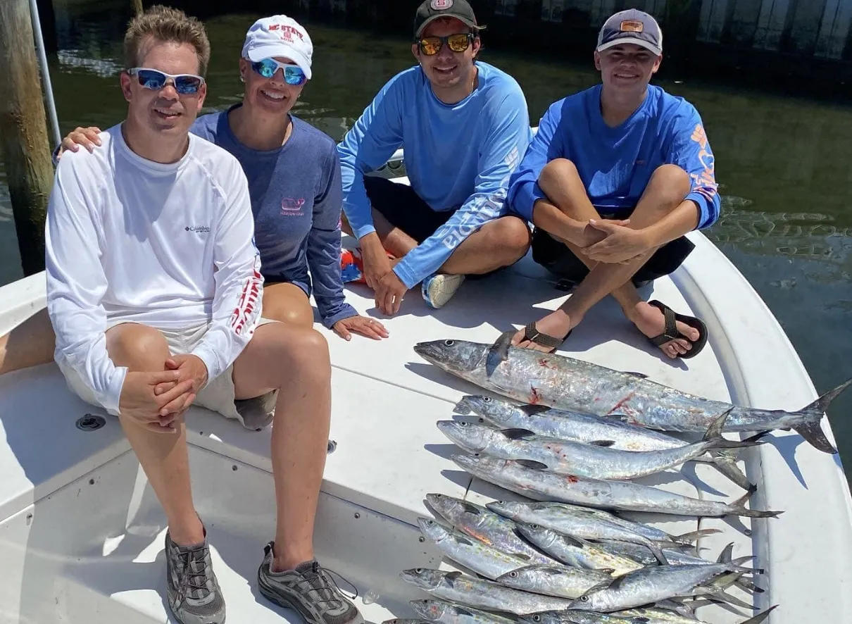 A happy family reeling in a big catch on a fishing charter in Atlantic Beach.